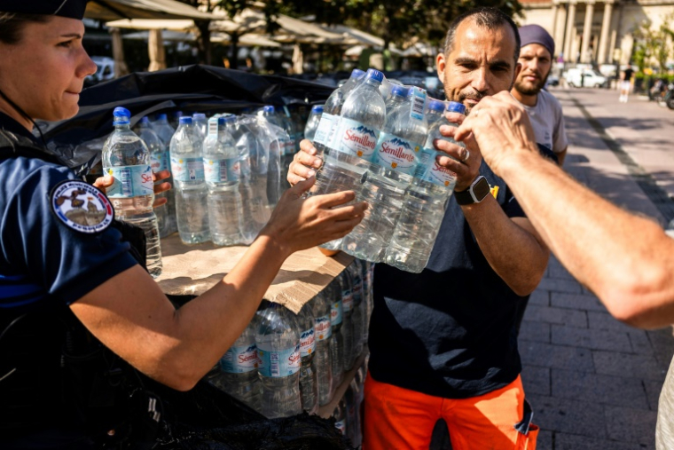 Des employés municipaux donnent des packs d'eau aux habitants lors d'une distribution d'eau potable à la suite d'une rupture de canalisation à Perpignan, le 16 juin 2025 dans les Pyrénées-Orientales ( AFP / Jc Milhet )