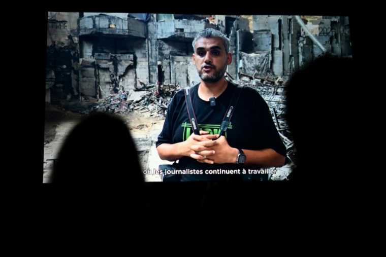Le photographe palestinien Mahmoud Abu Hamda prononce un discours préenregistré, diffusé sur écran, après avoir reçu le prix du jury international de l'édition 2026 du Prix Bayeux Calvados-Normandie des correspondants de guerre, à Bayeux, le 10 octobre 2026 ( AFP / Guillaume Saligot )