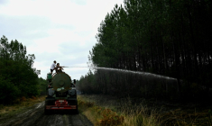 Des agriculteurs aspergent d'eau des points chauds pour aider les pompiers à combattre l'incendie à Saint-Jean-d'Illac, à l'ouest de Bordeaux, le 27 juillet 2026 ( AFP / Philippe Lopez )