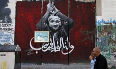 Des hommes marchent devant un portrait du dirigeant palestinien Marwan Barghouti peint sur la barrière séparant la Cisjordanie occupée d'Israël le 6 novembre 2023 à Bethléem.  ( AFP / HAZEM BADER )