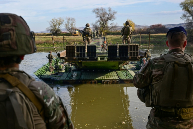 Le 3 novembre 2025 à Santimbru, en Roumanie, des militaires du génie de combat de l'Armée de terre française manœuvrent un pont flottant motorisé (PFM) sur la rivière Mureș lors de l'exercice  Dacian Fall de l'Otan ( AFP / Daniel MIHAILESCU )