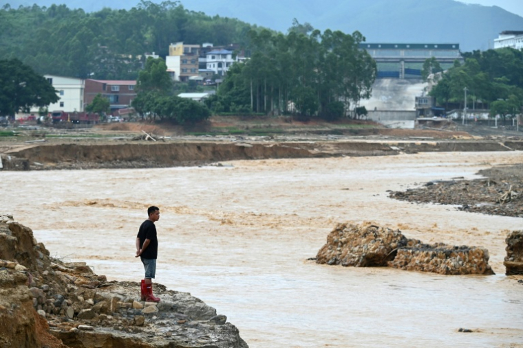 Un homme regarde l’eau s’écouler du réservoir effondré de Liulan, dans le village de Liulan, dans la ville de Hengzhou, dans la région du Guangxi, au sud-ouest de la Chine, le 8 juillet 2026 ( AFP / GREG BAKER )