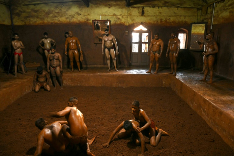 Le lutteur profesionnel Mauli Jamdade (c), aux côtés d'autres lutteurs, regarde un entraînement de juniors dans un gymnase à Kolhapur, dans l'État du Maharashtra, le 30 avril 2025 en Inde ( AFP / Indranil MUKHERJEE )