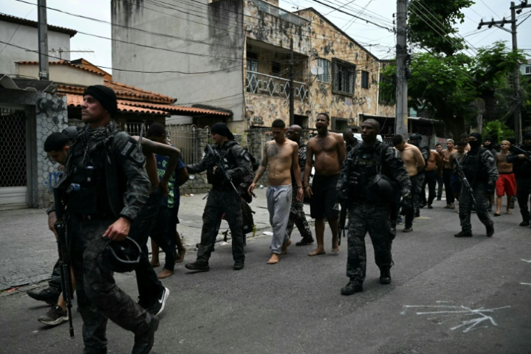Des policiers escortent des criminels présumés arrêtés lors d'une opération dans la favela de Vila Cruzeiro, dans le complexe de Penha, à Rio de Janeiro, le 28 octobre 2025 au Brésil ( AFP / Mauro PIMENTEL )
