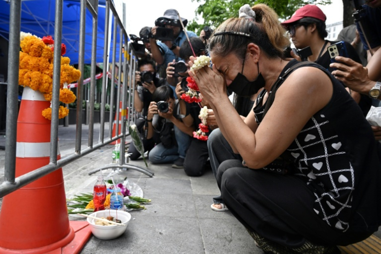 Une femme endeuillée prie sur les lieux de l'incendie dans le bar Rong Beer Na Lat Phrao, le 14 juillet 2026 à Bangkok, en Thaïlande ( AFP / Lillian SUWANRUMPHA )
