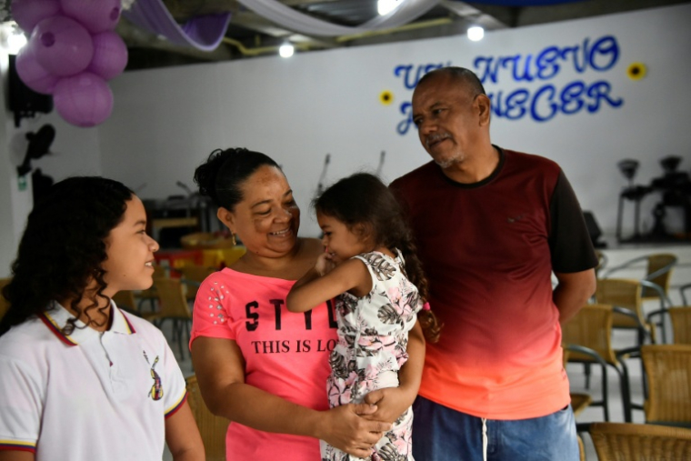Franklin Petit (d), aide-maçon, sa femme Nellisbeth Martinez (2e g), couturière, et leurs enfants à l'église du quartier Trigal del Norte, près de Cucuta, le 8 janvier 2026 en Colombie ( AFP / Schneyder MENDOZA )